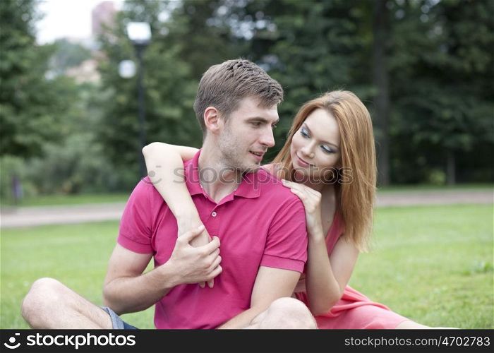 Young beautiful couple lovers, against green of summer park.