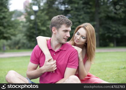 Young beautiful couple lovers, against green of summer park.