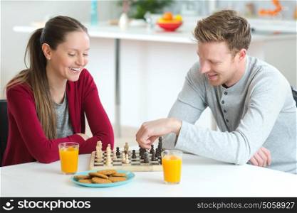 young beautiful couple playing chess indoor