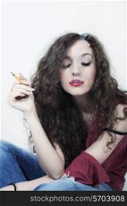 Young beautiful curly long-haired brunette woman with cigarette isolated on white background