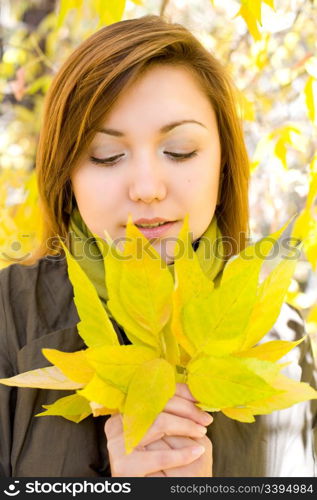 young beautiful european girl looks at bunch of autumn leaves in her hands