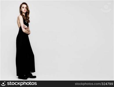 Young beautiful fashion model wearing black dress on grey background