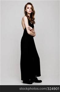 Young beautiful fashion model wearing black dress on grey background