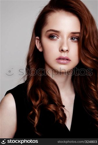 Young beautiful fashion model wearing black dress with no sleeves on grey background using hard light