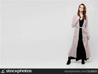 Young beautiful fashion model wearing knitwear dress on grey background