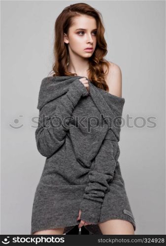 Young beautiful fashion model wearing knitwear jumper on grey background
