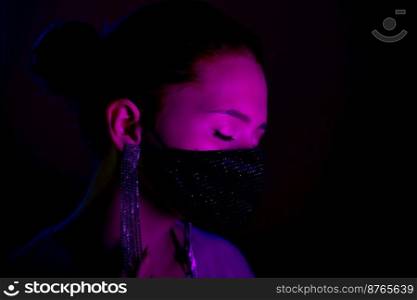 Young beautiful fashionable woman in protective mask with rhinestones dancing in bar or club. High quality photo. Young beautiful fashionable woman in protective mask with rhinestones dancing in bar or club.