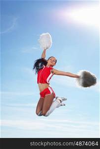 Young beautiful female cheerleader in uniform jumping high. Young female cheerleader
