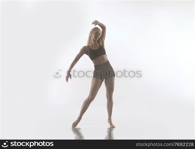 young beautiful female sporty dancer in black tights performing modern style ballet making acrobatic elements   female ballet dancer in art performance in front of white background