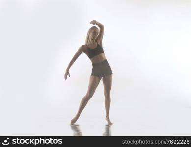 young beautiful female sporty dancer in black tights performing modern style ballet making acrobatic elements   female ballet dancer in art performance in front of white background