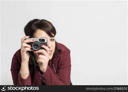 Young beautiful female taking a photo with a retro camera