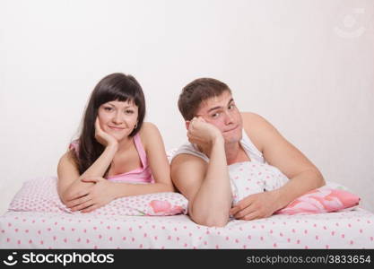 Young beautiful girl and the guy in bed resting in bed