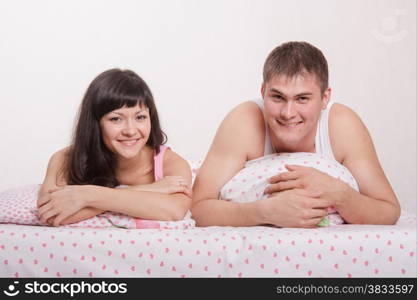 Young beautiful girl and the guy kissing and cuddling in bed