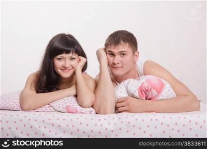Young beautiful girl and the guy kissing and cuddling in bed