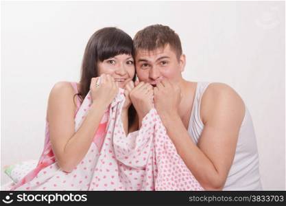 Young beautiful girl and the guy sitting in bed cuddling