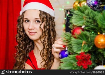 Young beautiful girl decorates Christmas tree toys. young girl dresses up Christmas tree