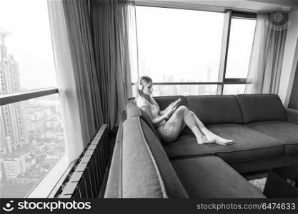 Young beautiful girl enjoying music through headphones, laying on sofa near the window at home. young girl enjoying music through headphones