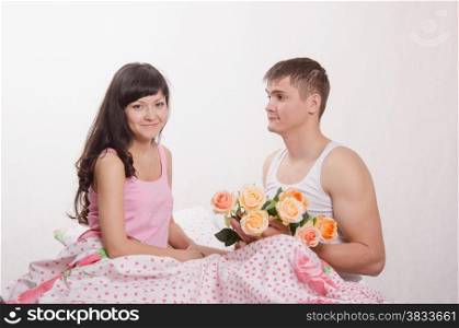Young beautiful girl gives flowers to a young guy