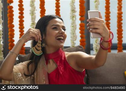 young beautiful girl happily trying on earrings and looking in to the phone
