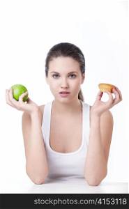 Young beautiful girl holding a green apple and cake on a white background