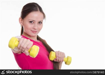 Young beautiful girl holds Europeans physical exercise. She held out her hand with a dumbbell