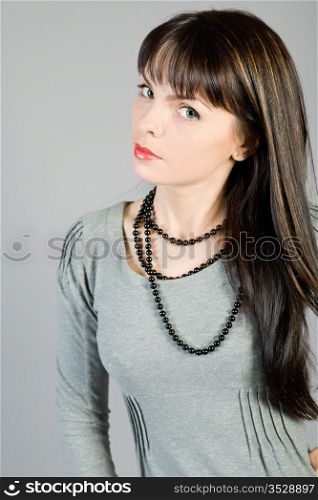 young beautiful girl in a blouse on a grey background. Portrait of the woman