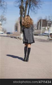 Young beautiful girl in a gray coat - back view