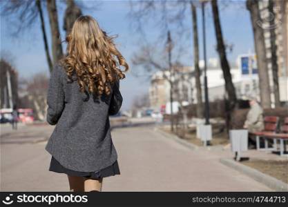Young beautiful girl in a gray coat - back view