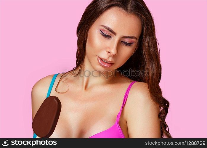 young beautiful girl in a swimsuit with ice cream on a pink isolated background. summer concept