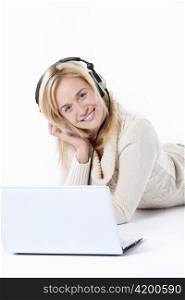 Young beautiful girl in headphones with a laptop on a white background