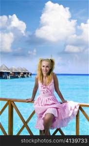 Young beautiful girl in pink sundress on villa on water , Maldives