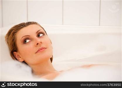 Young beautiful girl is relaxing in a bathtub with foam