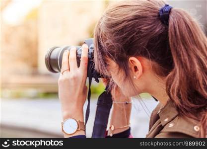 Young beautiful girl is taking a picture with her camera. View from behind.