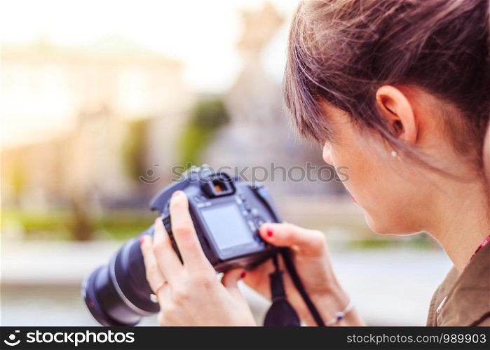 Young beautiful girl is taking a picture with her camera. View from behind.
