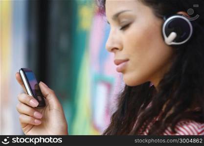 Young beautiful girl listening to MP3 player on the street