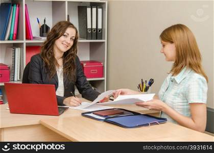 Young beautiful girl on reception at the office specialist. Head gladly sign the documents prepared by the expert