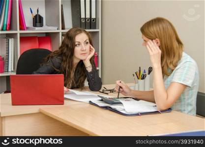 Young beautiful girl on reception at the office specialist. Two women talking in the office and dealt with in the accounts