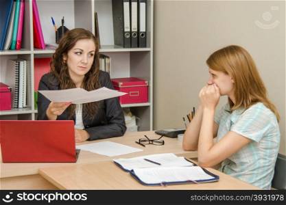 Young beautiful girl on reception at the office specialist. Head scolds specialist office for improperly prepared documents