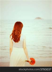 Young beautiful girl on the beach holding flower with retro filter effect