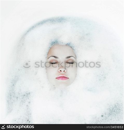 Young beautiful girl relaxing in the bath with foam