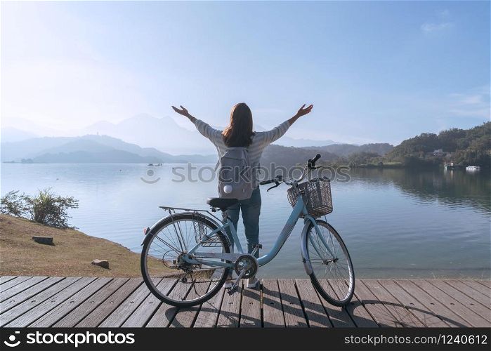 young beautiful girl stand near a bicycle while rest up her hands on bike trail at the lake in the morning. Active people. Outdoors
