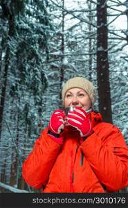 young beautiful girl with a metal mug of hot tea in the winter forest