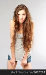 young beautiful girl with long curly hair wearing mini short jeans and looking in camera
