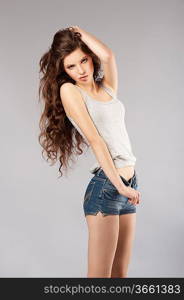 young beautiful girl with long curly hair wearing mini short jeans and posing