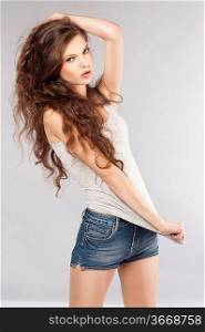 young beautiful girl with long curly hair wearing mini short jeans and posing