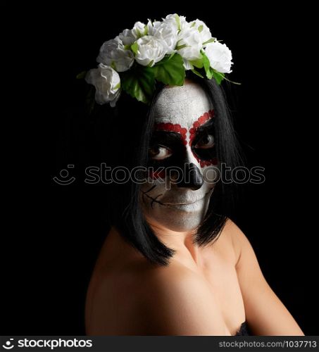 Young beautiful girl with traditional mexican death mask. Calavera Catrina. Sugar skull makeup. girl dressed in a wreath of white roses