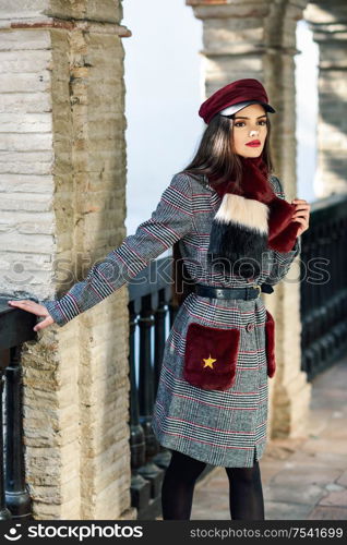 Young beautiful girl with very long hair looking away wearing winter coat and cap outdoors. Lifestyle and fashion concept.. Young beautiful girl with very long hair looking away wearing winter coat and cap outdoors.