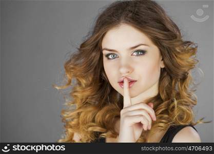 Young beautiful haired woman has put forefinger to lips as sign of silence