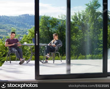 young beautiful handsome couple enjoying morning coffee and breakfast in front of their luxury home villa