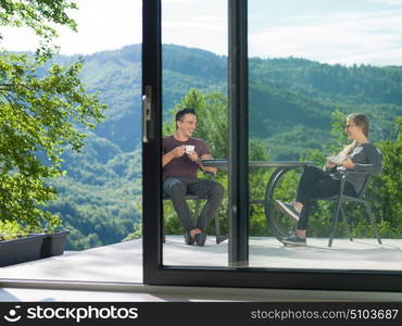 young beautiful handsome couple enjoying morning coffee and breakfast in front of their luxury home villa